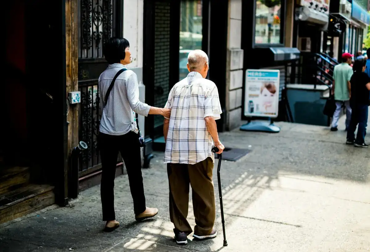 Younger companion supporting an older adult walking in the city